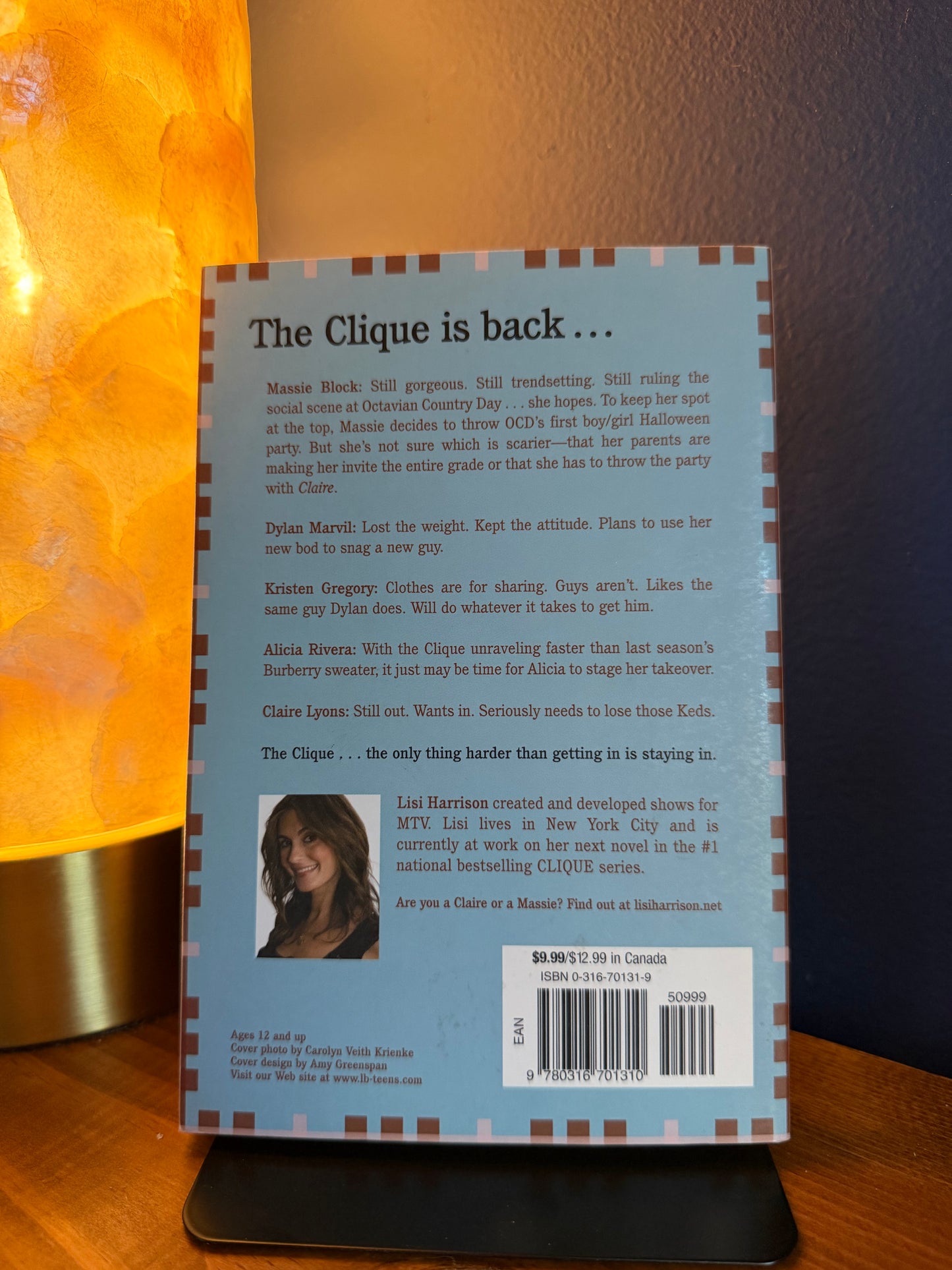 Back cover of a book with text and a photo of a girl on a wooden surface.