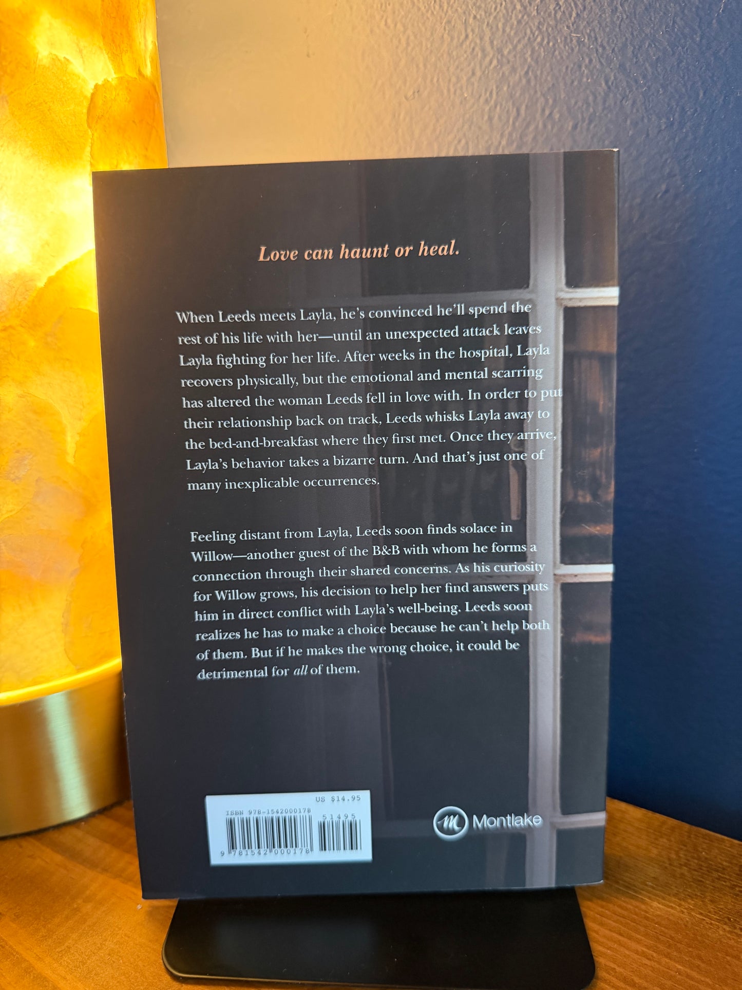 Back cover of a book with text and a logo on a wooden surface