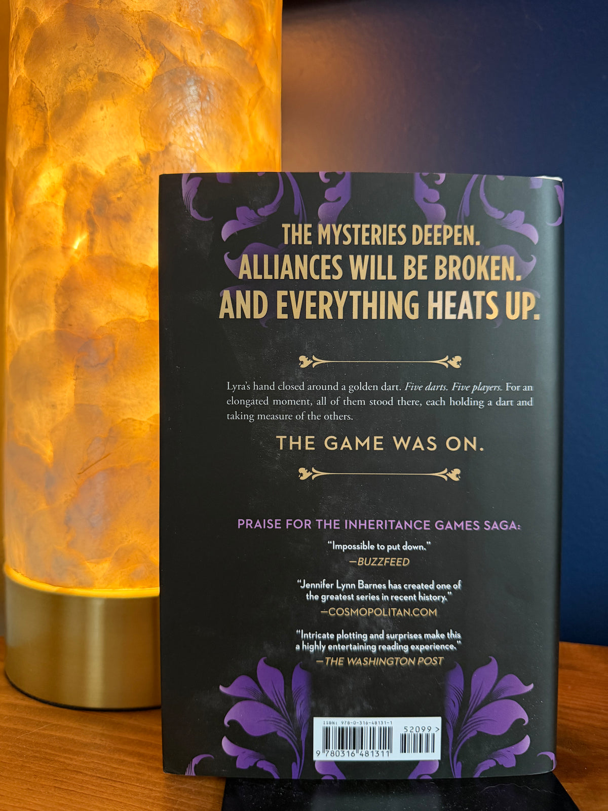 Book cover with promotional text on a stand next to a lamp