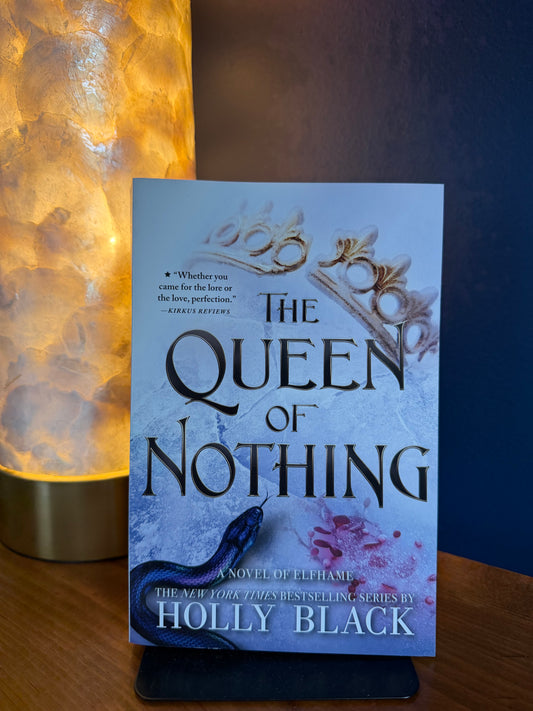 Book titled 'The Queen of Nothing' by Holly Black on a stand with a warm light source.