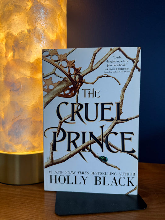 Book titled 'The Cruel Prince' by Holly Black on a wooden surface with a warm light.