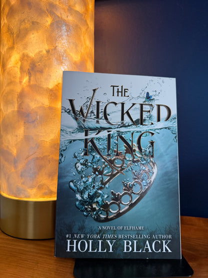 Book titled 'The Wicked King' by Holly Black on a wooden surface with a blurred background